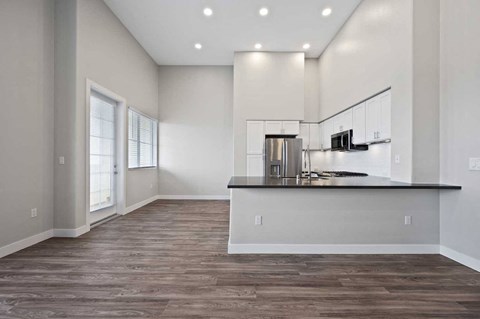 an empty living room with a kitchen and a counter top